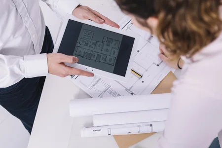 Personas trabajando con tablet sobre planos de arquitectura